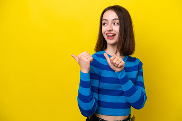 Young Ukrainian woman isolated on yellow background pointing to the side to present a product