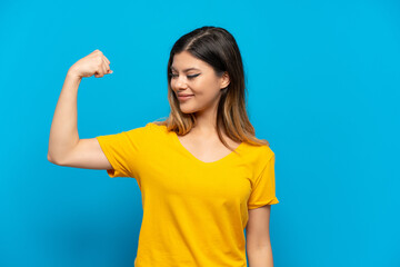 Young Russian girl isolated on blue background doing strong gesture