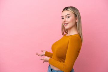 Young caucasian woman isolated on pink background extending hands to the side for inviting to come