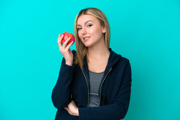 Young caucasian woman isolated on blue background with an apple