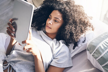 Tablet, black woman and relax in bed in bedroom for social media, texting or internet browsing in...