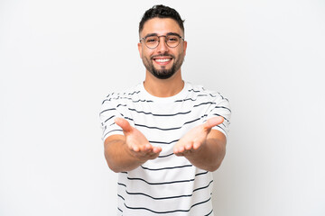 Young Arab handsome man isolated on white background holding copyspace imaginary on the palm to...