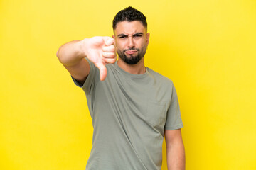 Young Arab handsome man isolated on yellow background showing thumb down with negative expression