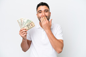 Young Arab man taking a lot of money isolated on white background happy and smiling covering mouth with hand