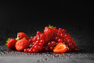 Strawberries and red currants on a dark background