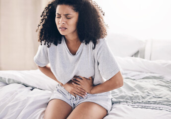 Abdomen pain, period and black woman in bed with abdominal cramps, menstruation and stomach ache. Health, medical emergency and girl with digestion problem, pms crisis and endometriosis in bedroom - obrazy, fototapety, plakaty