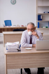 Fototapeta premium Old male employee drinking coffee during break
