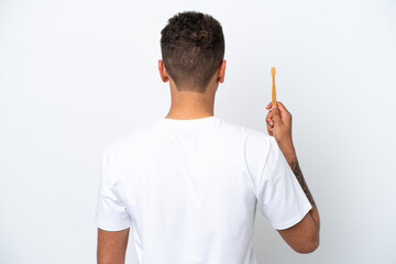 Young Brazilian man brushing teeth isolated on white background in back position