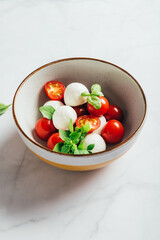Classic italian salad caprese served in original form with cherry tomatoes, mini mozarella pearls and basil