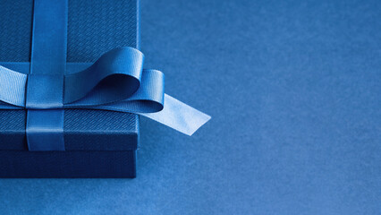 Luxury gift box with a blue bow on blue. High angle view monochrome close up. Fathers day or...