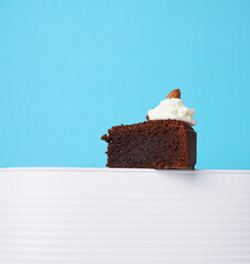 Chocolate brownie, cake on a white stand on a blue background. heroic view. Cope space