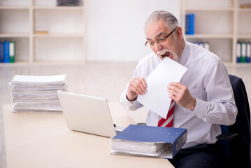 Obraz premium Old male employee and too much work at workplace