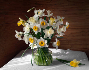 Still life with a bouquet of daffodils in glass vase on a table