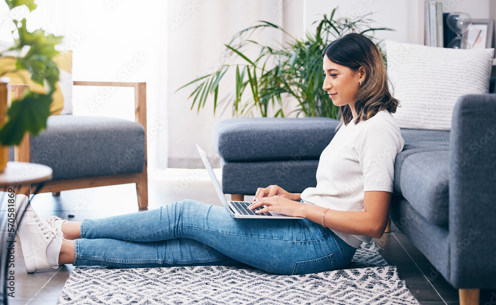Poster woman, laptop and typing sitting on floor in the living room by sofa in remote work or studying at h