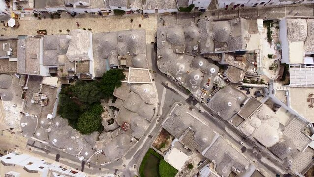 Aerial top down drone footage of Alberobello, Puglia, Italy. The traditional whitewashed, conical roof (trulli) UNESCO world heritage site, landmark tourist destination from above.