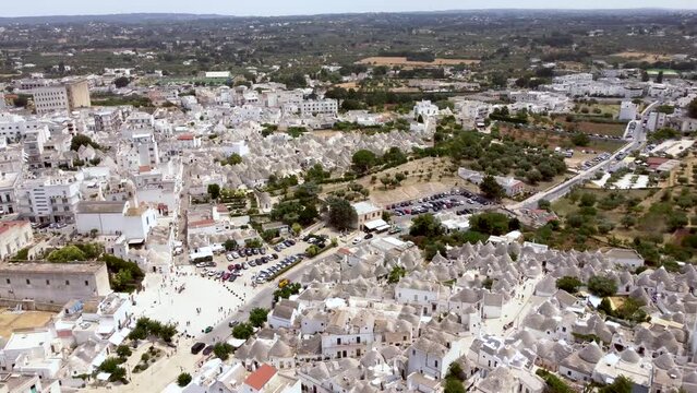 Aerial drone footage of Alberobello, Puglia, Italy. Reveal scene of the traditional whitewashed, conical roof (trulli) UNESCO world heritage site, landmark tourist destination from above.