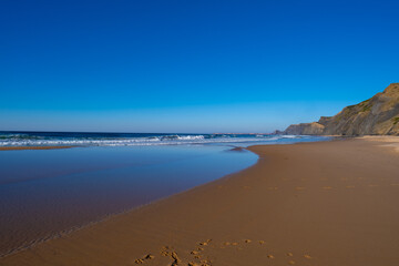 Fototapeta na wymiar Peaceful and beautiful coast of Portugal. Beautiful ocean beach landscape. Blue sky. Sand.