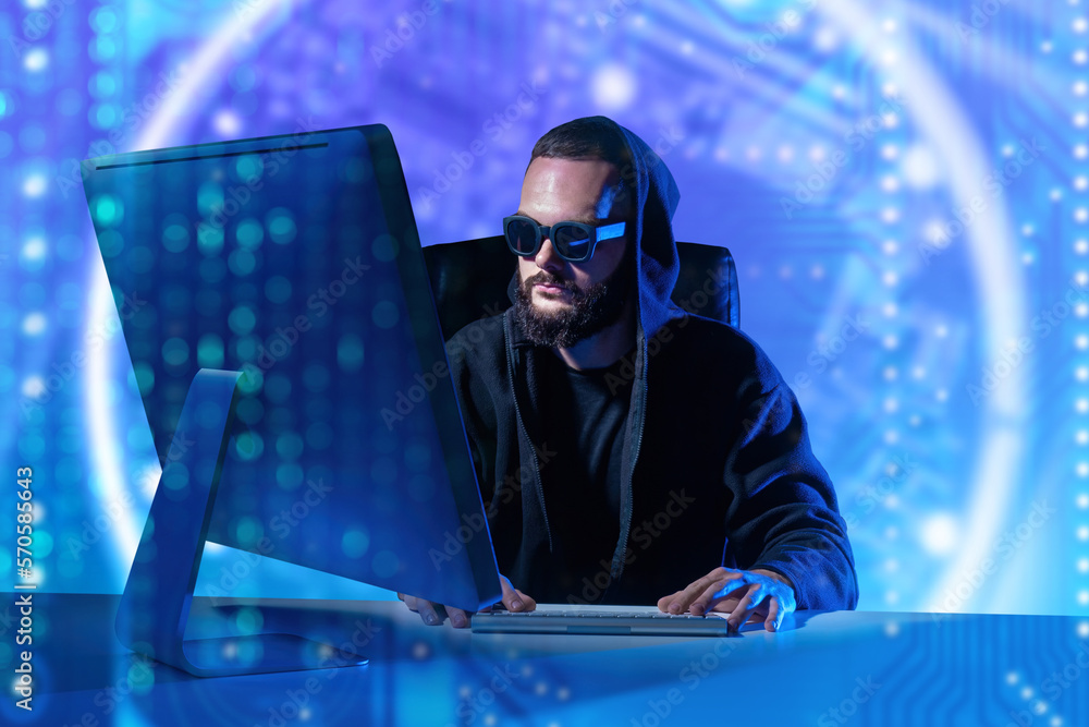 Poster male it-developer near monitor. guy is programming sitting at table. man geek in hood and sunglasses