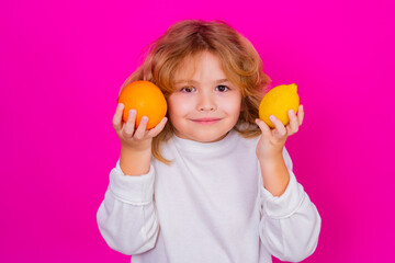 Vitamin and healthy fruits for kids. Kid with orange and lemon in studio. Studio portrait of cute child hold lemon and orange isolated on pink background.