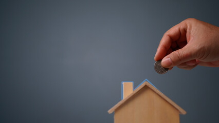Fototapeta na wymiar hand putting coin money in bank wooden house model