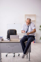 Old male employee doing sport exercises at workplace