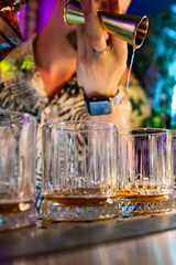 Bartender hand pouring whiskey on glass in bar