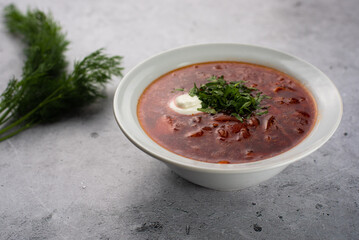 Red delicious delicious borscht in a white plate on a gray background