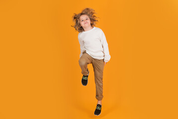 Funny boy jumping in air. Full body of little child jump wear casual t-shirt and jeans isolated on yellow background.