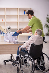 Fototapeta premium Old patient in wheel-chair visiting skeleton doctor