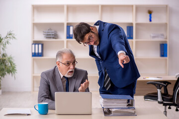 Old male boss and young male employee in the office
