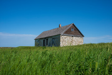 An abandoned cobblestone farm house stands in the grasslands of Dickinson, North Dakota during an...