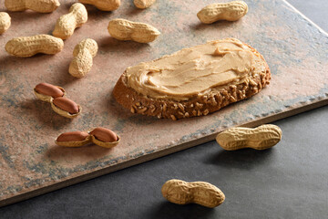 Peanut butter on a bread slice with shelled peanuts, still life