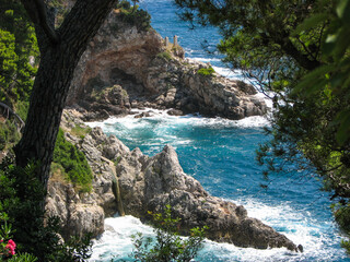 Turquoise water splashing against a rocky shore near Dubrovnik, Croatia.  Image has copy space.