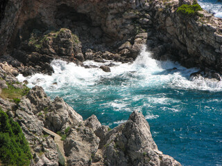 Turquoise water splashing against a rocky shore near Dubrovnik, Croatia.  Image has copy space.