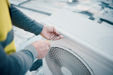 Hands, air conditioner and maintenance with a man construction worker on a rooftop to install a...