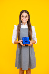 Teenager child girl holding present box isolated over yellow studio background. Present, greeting and gifting concept. Birthday holiday concept.