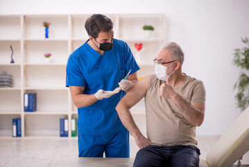 Fototapeta premium Old male patient visiting young male doctor in vaccination conce