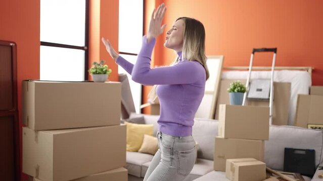 Young blonde woman smiling confident dancing at new home