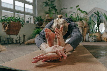 Man sitting in Paschimottanasana on cork mat in yoga studio