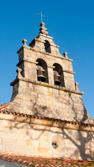Fototapeta na wymiar Sombra de ramas de arbol en fachada de iglesia de piedra en pueblo