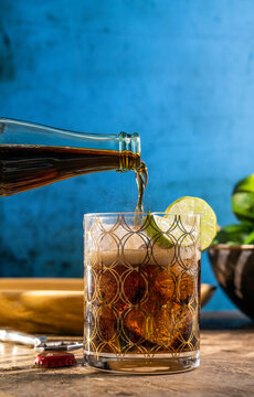 Cuba libre cocktail served in a rocks glass garnished with lime 