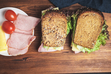 Sandwiches with a ham, cheese, tomato, salad lettuce on a wooden board , top view