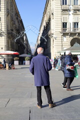 Un anziano prende un po' di sole e guarda verso via Garibaldi da piazza Castello a Torino
