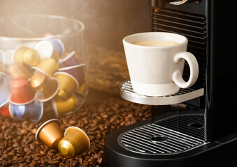 Coffee capsules pods on raw beans with espresso cup and home coffee machine.