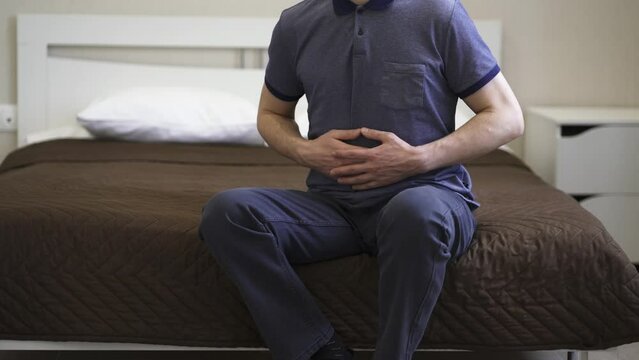 Stomach ache, man with abdominal pain suffering at home, health problems concept
