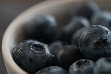 Closeup shot of washed blueberries in white bowl on wood table