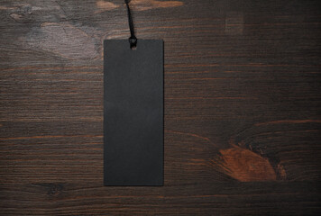 Blank black price tag on wooden background. Copy space for text.