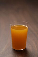 Fresh orange juice in thin glass on wooden table with copy space