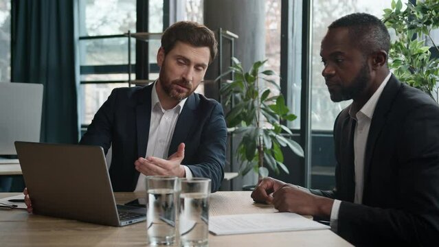 Two diverse businessmen multiracial men at office with laptop. Caucasian financial advisor manager consultant insurance agent consulting African American man client talk show business presentation
