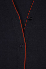 dark blue neck cardigan with red trim and black buttons